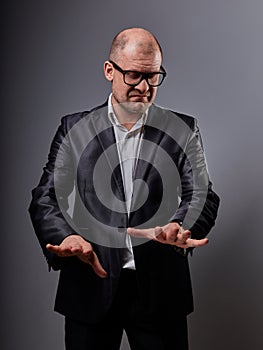 Unhappy depressed busuness man in black suit and glasses showing the palm shut down sign on grey background. Closeup