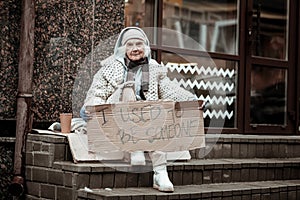 Unhappy depressed homeless woman holding a sign