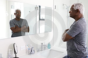 Unhappy Depressed Senior Man Looking At Reflection In Bathroom Mirror