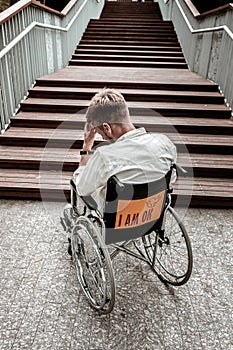 Unhappy disabled man sitting in wheelchair and facing a problem