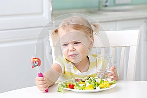 Unhappy displeased child eating healthy food