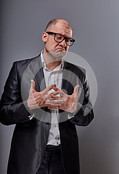 Unhappy doubt busuness man in black suit and glasses showing the palm refusing sign on grey background