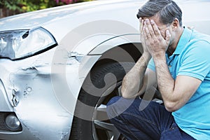 Unhappy Driver Inspecting Damage After Car Accident photo