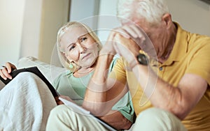 Unhappy elderly couple sitting on a sofa together and looking stressed. Senior caucasian man and woman looking worried