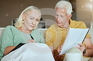 Unhappy elderly couple sitting on a sofa together and looking stressed. Senior caucasian man and woman looking worried