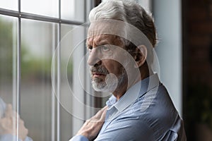 Unhappy elderly man look in distance pondering