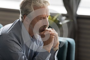 Unhappy elderly man look in distance thinking of past