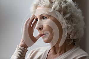 Unhappy elderly woman lost in thoughts in retirement house