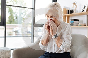Unhappy elderly woman sneezing photo