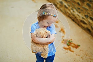 Unhappy and emotional toddler girl sitting on the floor outdoors