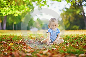 Unhappy and emotional toddler girl sitting on the ground in park