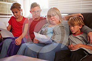 Unhappy Family Sitting On Sofa Looking At Bills