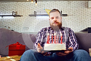 Unhappy fat man with cake birthday in the room.