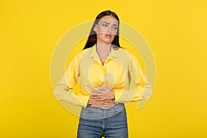 Unhappy Female Suffering From Stomachache Touching Abdomen On Yellow Background