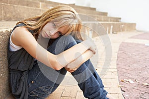 Unhappy Female Teenage Student Sitting Outside