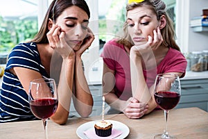 Unhappy friends sitting at table during birthday party