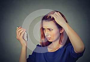 Unhappy frustrated upset woman surprised she is losing hair, receding hairline