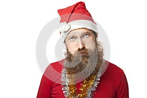 Unhappy funny santa claus with real beard and red hat and shirt looking at camera with sadness. isolated on white