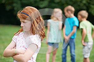 Unhappy Girl Being Gossiped About By Other Children