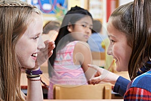 Unhappy Girl Being Gossiped About By School Friends In Classroom