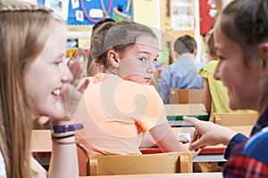 Unhappy Girl Being Gossiped About By School Friends In Classroom