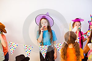 Unhappy girl is blowing whistle at bithday party. Negative emotion and feelings.