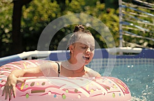 Unhappy girl child swim in donut pool float on sunny summer day, floating