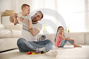 Unhappy girl feeling jealous while father spending time with her baby brother at home