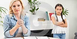 Unhappy girl not talking after an argument with mother in the living room at home