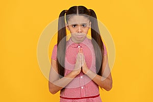 Unhappy girl prayer plead holding palms together in prayer gesture yellow background, pleading