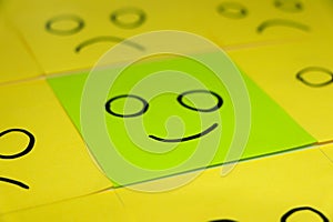 Unhappy and happy concept. Background of green sticky notes. Unhappy sticky note is among happy sticky notes