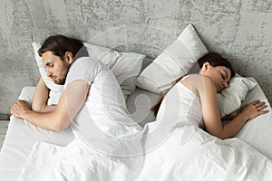 Unhappy indifferent couple sleeping separately back to back in b