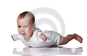 Unhappy infant baby boy toddler in diaper and white bodysuit is lying on floor on his stomach and crying