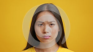 Unhappy Japanese Woman Looking At Camera Posing Over Yellow Background