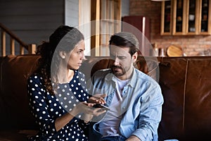 Unhappy jealous woman arguing with man, holding smartphone, family conflict
