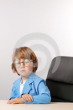 Unhappy kid in blue stylish suit managing with children
