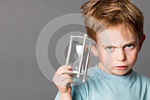 Unhappy little boy with an egg timer for time concept
