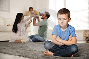 Unhappy little boy feeling jealous while parents spending time with his baby brother