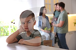 Unhappy little boy feeling jealous while parents spending time with his sister