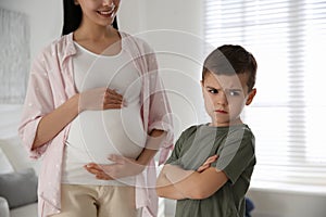 Unhappy little boy near pregnant mother. Feeling jealous towards unborn sibling