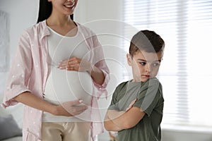 Unhappy little boy near pregnant mother. Feeling jealous towards unborn sibling