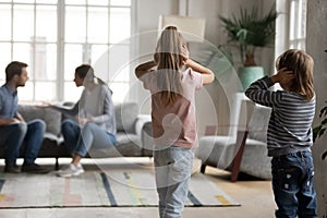 Unhappy little children looking at arguing parents.