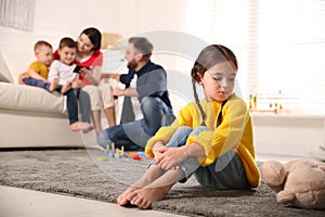 Unhappy little girl feeling jealous while parents spending time with other children