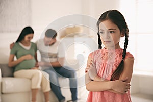 Unhappy little girl and her father with pregnant mother. Feeling jealous towards unborn sibling