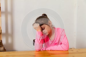 Unhappy little girl nine years old sitting at table