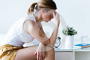 Unhappy lonely depressed young woman sitting on bed at home. Depression concept. photo