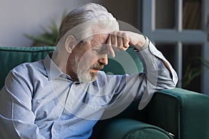 Unhappy lonely grey haired mature man sitting on couch photo