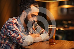 Unhappy lonely man drinking beer at bar or pub