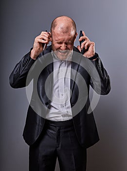 Unhappy loud crying anger business man talking on two mobile phones very emotional in office suit on grey background. Closeup