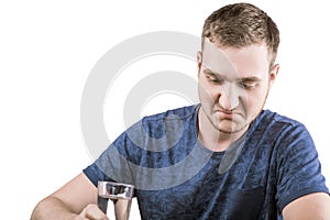 An unhappy male in a dark blue T-shirt is taking medicine pills, isolated on a white background.